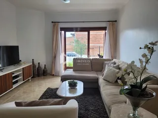 Sala de estar com sofá e porta de vidro que dá para o exterior.