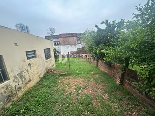 Vista externa de uma propriedade com jardim e muro de tijolos.