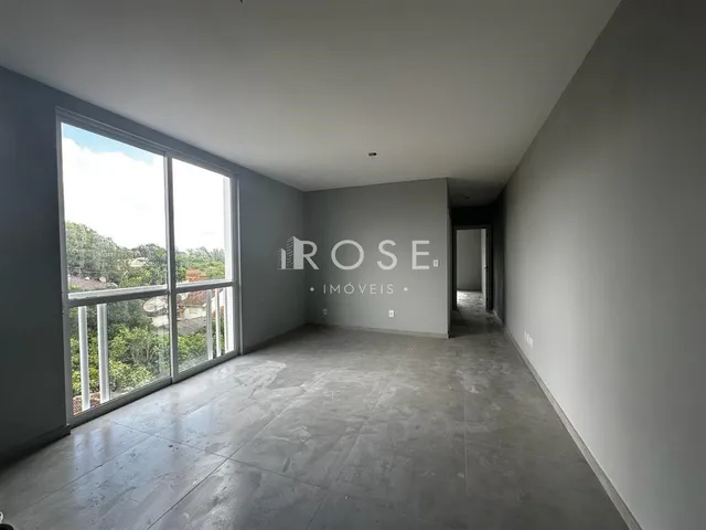 Interior de uma sala com grande janela e piso de concreto em um imóvel.