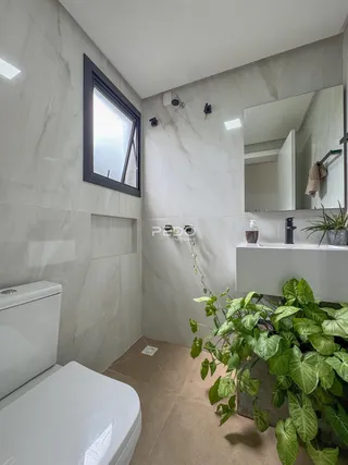 Interior de um banheiro moderno com revestimento em mármore claro.