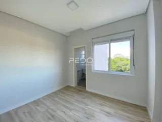 Ambiente interno de uma sala com piso de madeira clara e janela.