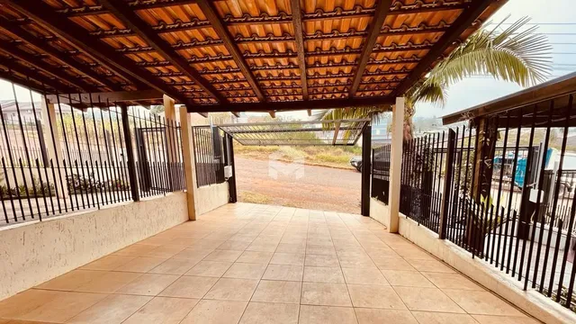 Vista de uma área externa coberta com piso de cerâmica e grade de metal.