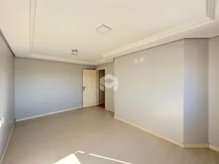 Interior de uma sala ampla com piso de madeira clara e paredes brancas.