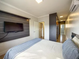 Quarto com cama e televisão montada na parede.