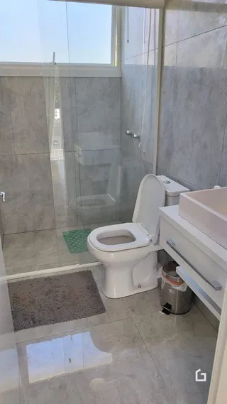 Foto de um banheiro com box de vidro e vaso sanitário.