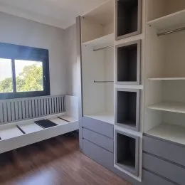 Interior com estantes e piso de madeira em um ambiente residencial.