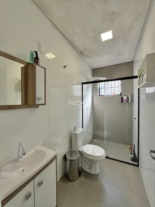 Banheiro com box de vidro e revestimento branco.