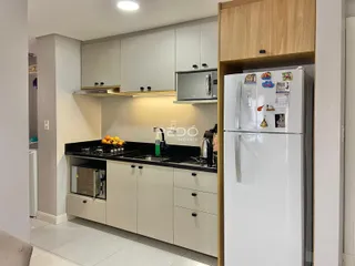 Cozinha moderna com armários brancos e bancadas escuras.
