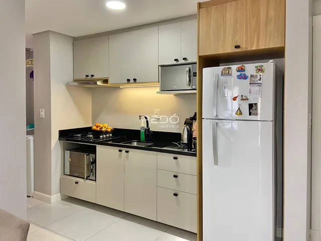 Cozinha moderna com armários brancos e bancadas escuras.