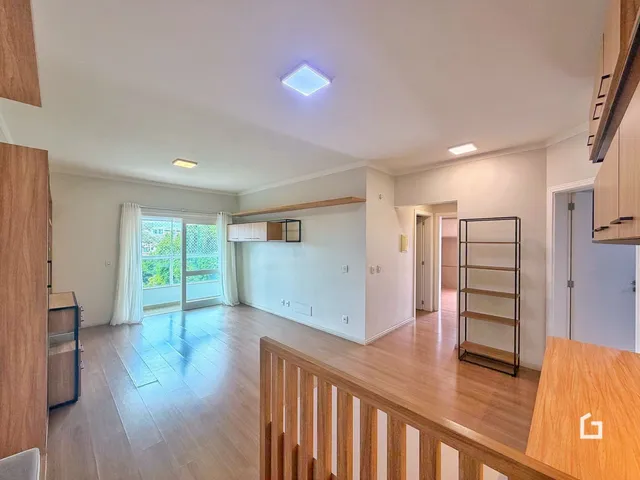 Sala de estar com piso de madeira e porta de vidro que dá para o exterior.