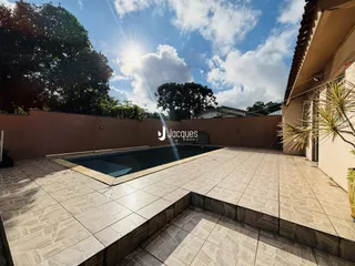 Vista externa de uma piscina e área de lazer com piso de cerâmica.