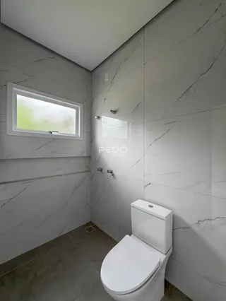 Banheiro com revestimento em mármore branco nas paredes e piso.