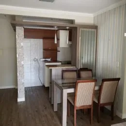 Foto interna de uma sala com piso de madeira e paredes brancas.