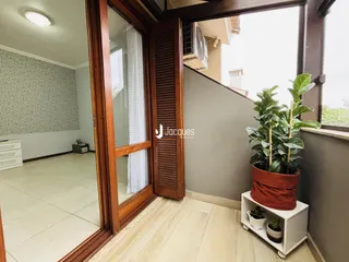 Sala de estar com piso claro e molduras de madeira na entrada.