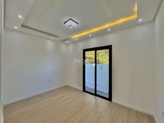 Uma sala de estar moderna com piso de madeira clara e porta de vidro.