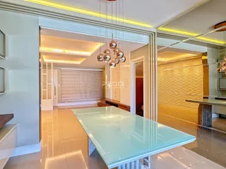Ambiente interno moderno com grande mesa de vidro em uma residência.