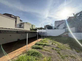Vista externa de um terreno com muro branco e vegetação