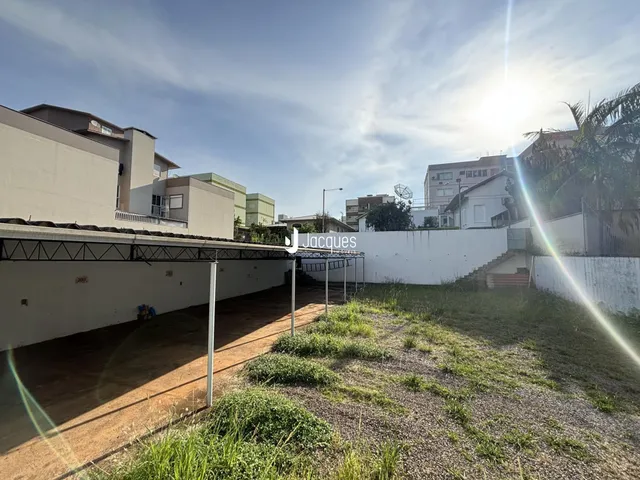 Vista externa de um terreno com muro branco e vegetação
