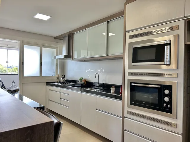 Vista da cozinha moderna com armários brancos e bancadas escuras.