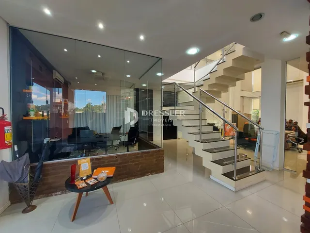 Ambiente interno moderno com grandes painéis de vidro e escadaria.