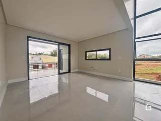 Ambiente interno de uma sala ampla com piso de cerâmica e portas de vidro em Lajeado, Brasil.