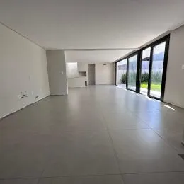 Hall de entrada com piso claro e grandes janelas que dão vista para o exterior.