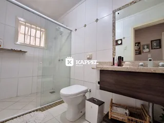 Banheiro com box de vidro e revestimento branco.