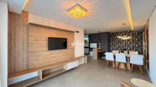 Sala de estar com painel de madeira e mesa de jantar.