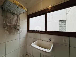 Foto interna de um ambiente com azulejos brancos e uma janela.