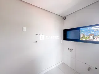 Vista de um corredor interno com paredes brancas e uma janela.