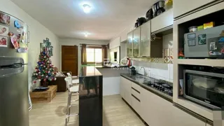 Sala de estar com cozinha integrada e piso de madeira clara.