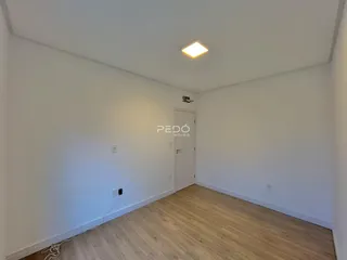 Interior de um cômodo com paredes brancas e piso de madeira clara.