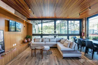 Sala de estar com piso de madeira e grandes janelas em um imóvel no Brasil.