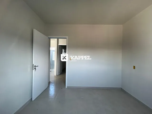 Hall de passagem com paredes brancas e piso claro.