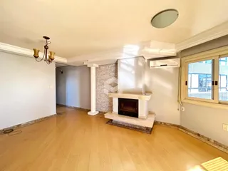 Sala de estar com piso de madeira clara e lareira em um imóvel no Brasil.