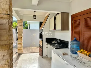 Vista interna de uma cozinha e área de estar com parede de pedra exposta.