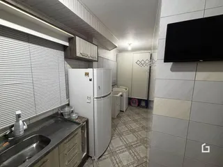 Vista interna de uma cozinha com bancada e eletrodomésticos brancos.
