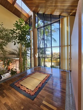 Interior com piso de madeira e grandes janelas em uma residência.
