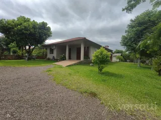 Vista externa de uma residência com gramado e paisagismo.