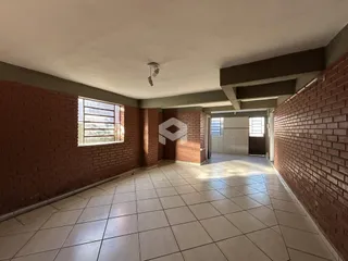 Corredor interno com paredes de tijolo aparente e piso de cerâmica.