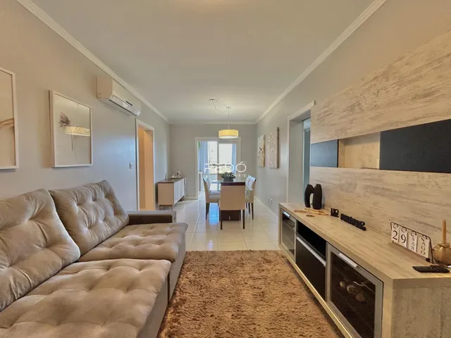 Sala de estar com sofá e área de cozinha em apartamento.