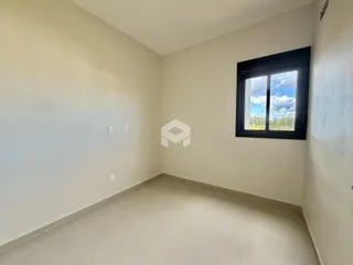 Uma sala de estar com paredes brancas e piso claro.