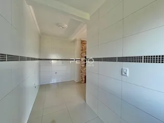 Corredor interno de uma residência com piso claro e paredes brancas.
