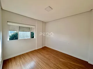 Ambiente interno de uma sala com piso de madeira e janela.