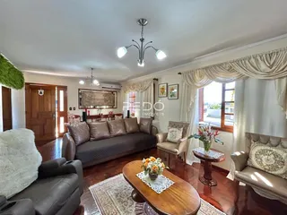 Sala de estar com piso de madeira e cortinas claras.