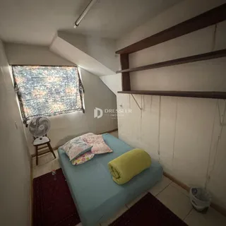 Quarto com cama e janela em ambiente com teto inclinado.