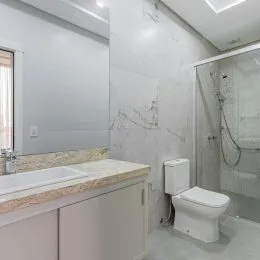 Foto de um banheiro com revestimento de azulejos brancos e bancada.