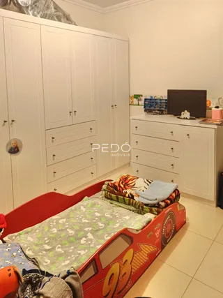 Quarto com armários brancos e cama vermelha em um imóvel no Brasil.