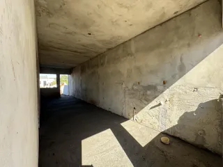 Corredor interno com paredes de concreto aparente e piso escuro.