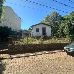 Vista externa de uma residência em Lajeado, Brasil, com paredes claras e vegetação ao fundo.